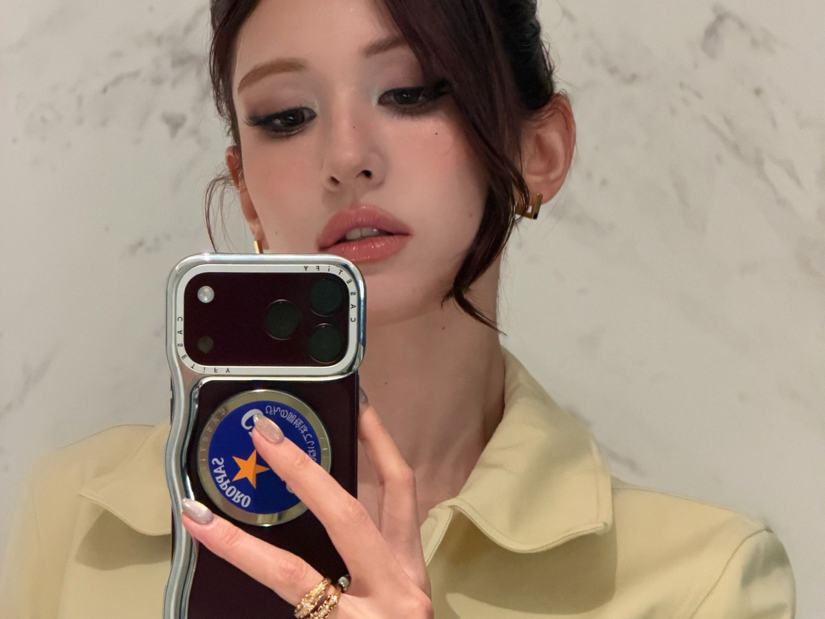 An Yujin taking a mirror selfie in yellow knitwear