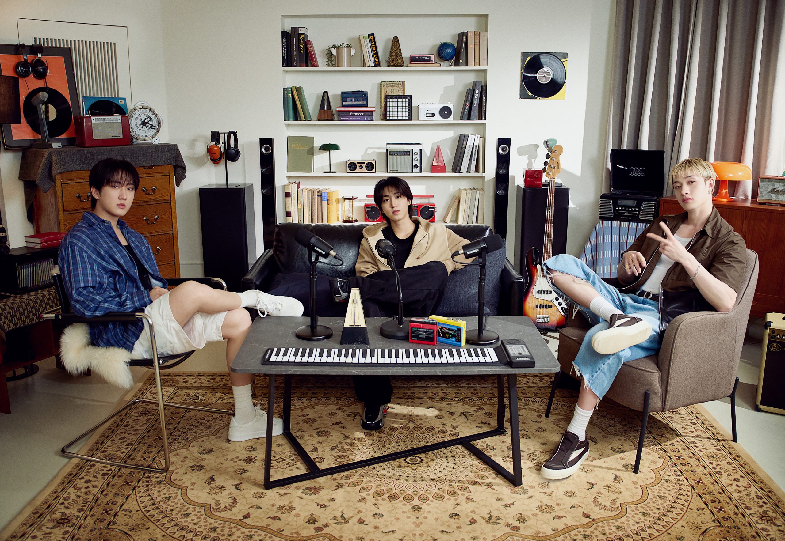 สมาชิก 3RACHA นั่งอยู่ในสตูดิโอที่มีเครื่องดนตรีและแผ่นเสียง