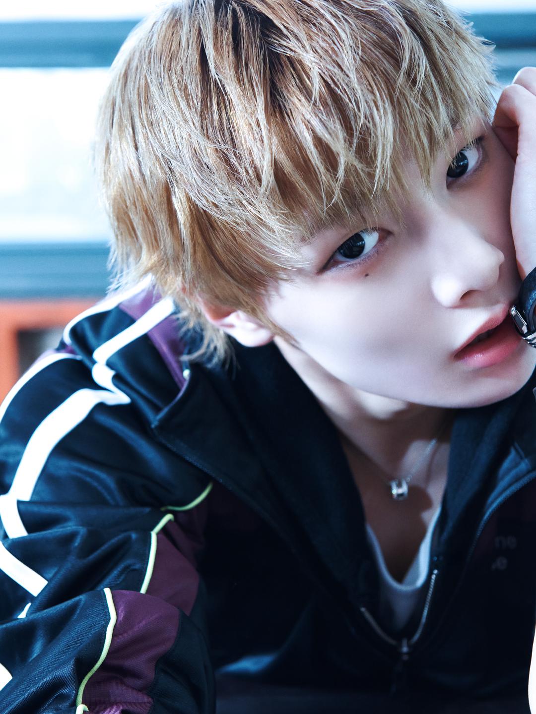 สมาชิก Stray Kids คนหนึ่งวางแขนพิงและมองกล้อง