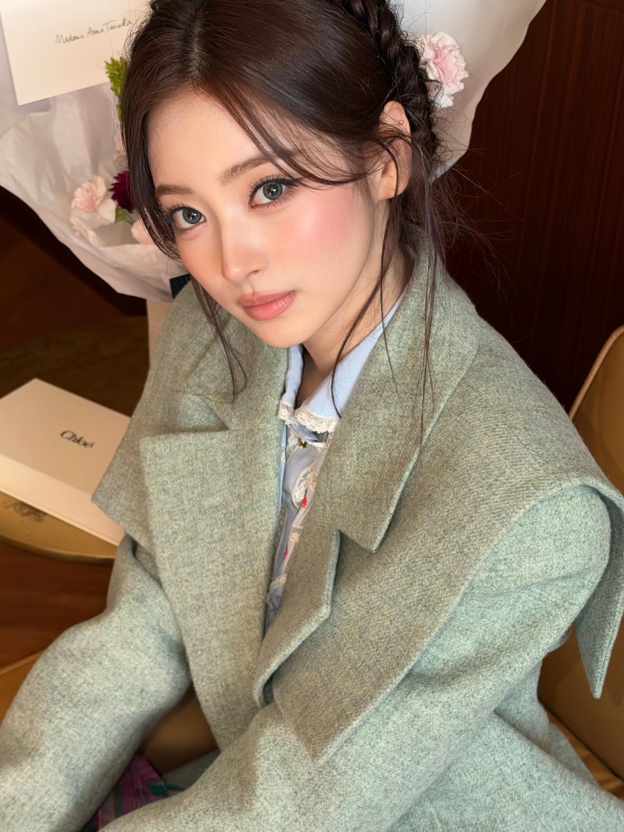 Anna wearing a green coat and muted lip makeup