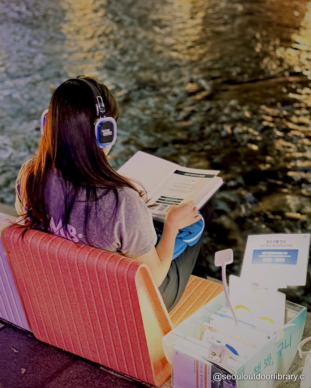 A reader wearing headphones beside Cheonggyecheon
